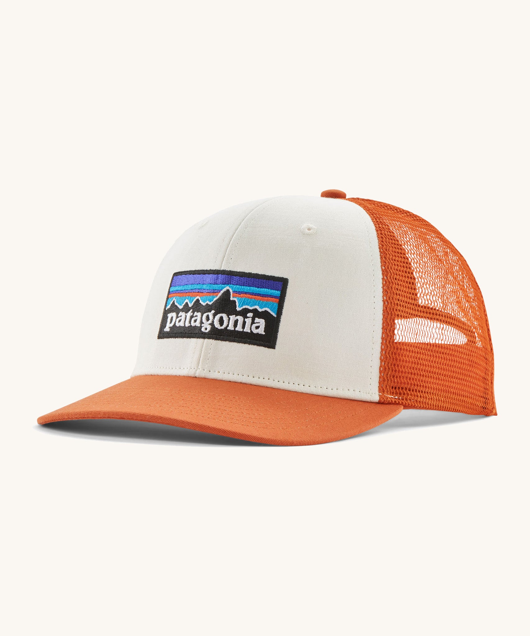 Patagonia adult trucker hat in white and orange colour on a cream background.