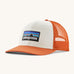 Patagonia adult trucker hat in white and orange colour on a cream background.