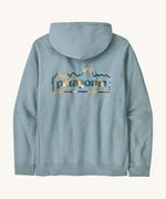 Patagonia adult unity hoodie in thermal lue with the logo design on the back on a cream backgroud.