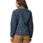 A woman wearing a Patagonia Women's Classic Retro-X jacket in a Utility Blue colour. The woman is facing away from the camera showing the back of the jacket. 