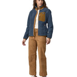 A woman wearing a Patagonia Women's Classic Retro-X jacket in a Utility Blue colour. The front zip of the jacket is fully opened. 
