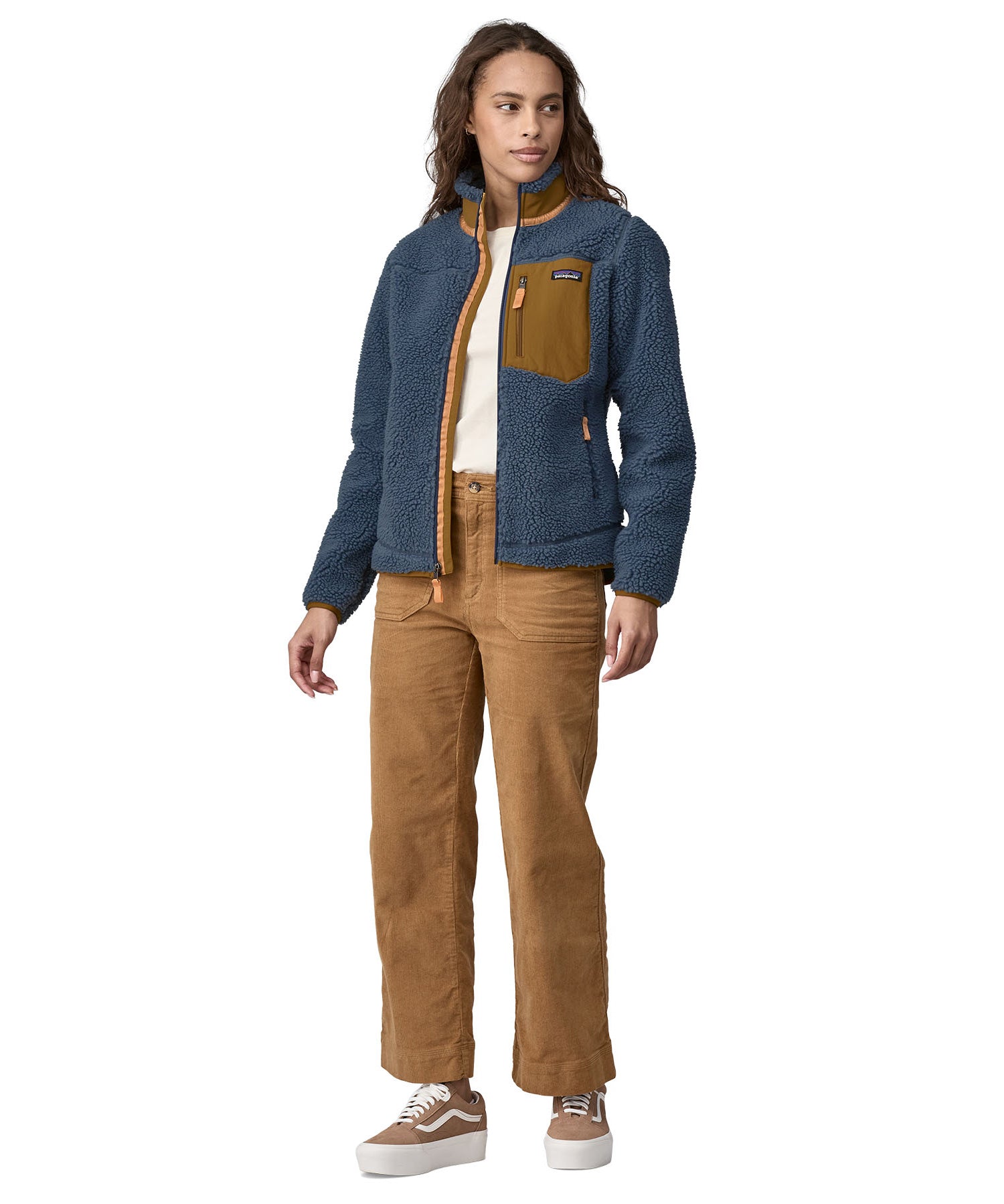 A woman wearing a Patagonia Women's Classic Retro-X jacket in a Utility Blue colour. The front zip of the jacket is fully opened. 