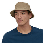 Man stood on a white background wearing the Patagonia mojave khaki bucket hat