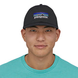 A man wearing the Patagonia black trucker logo cap available at Babipur.