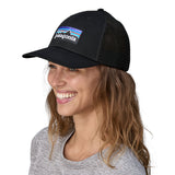 A woman wearing the Patagonia black trucker logo cap available at Babipur.