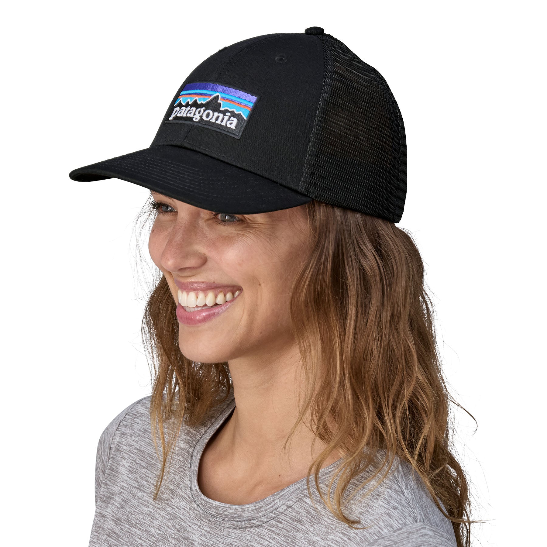 A woman wearing the Patagonia black trucker logo cap available at Babipur.