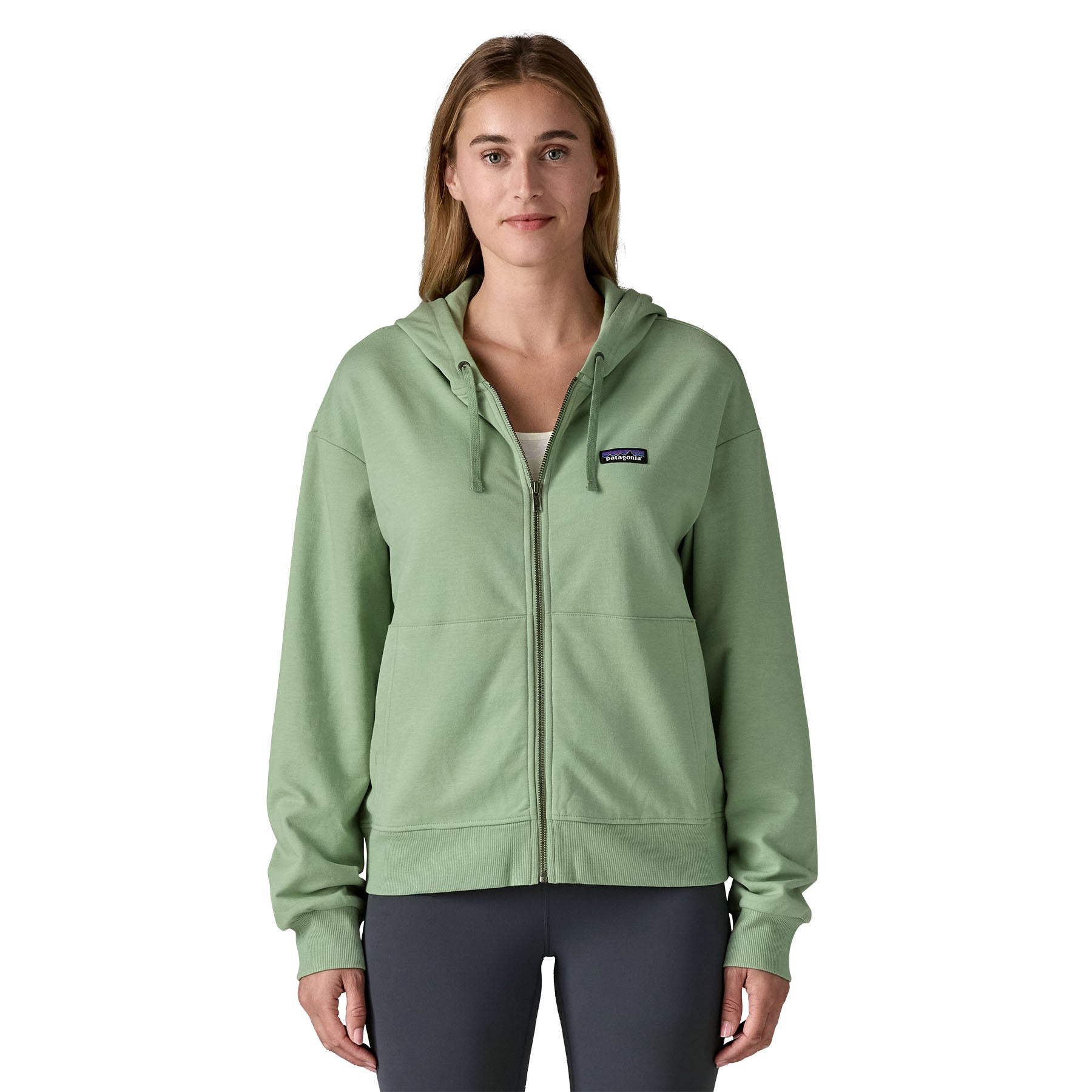 A woman wearing the Patagonia women's Anhya hoody available at Babipur. A pastel green lighweight jacket. Features a full length zip and 2 side pockets