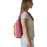 Person wearing the Patagonia atom cross body 8L sling bag in faded magenta with an orange front pocket over their shoulder.