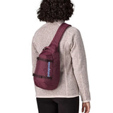 Person wearing a Patagonia atom sling 8L bag in berry fig on their back.