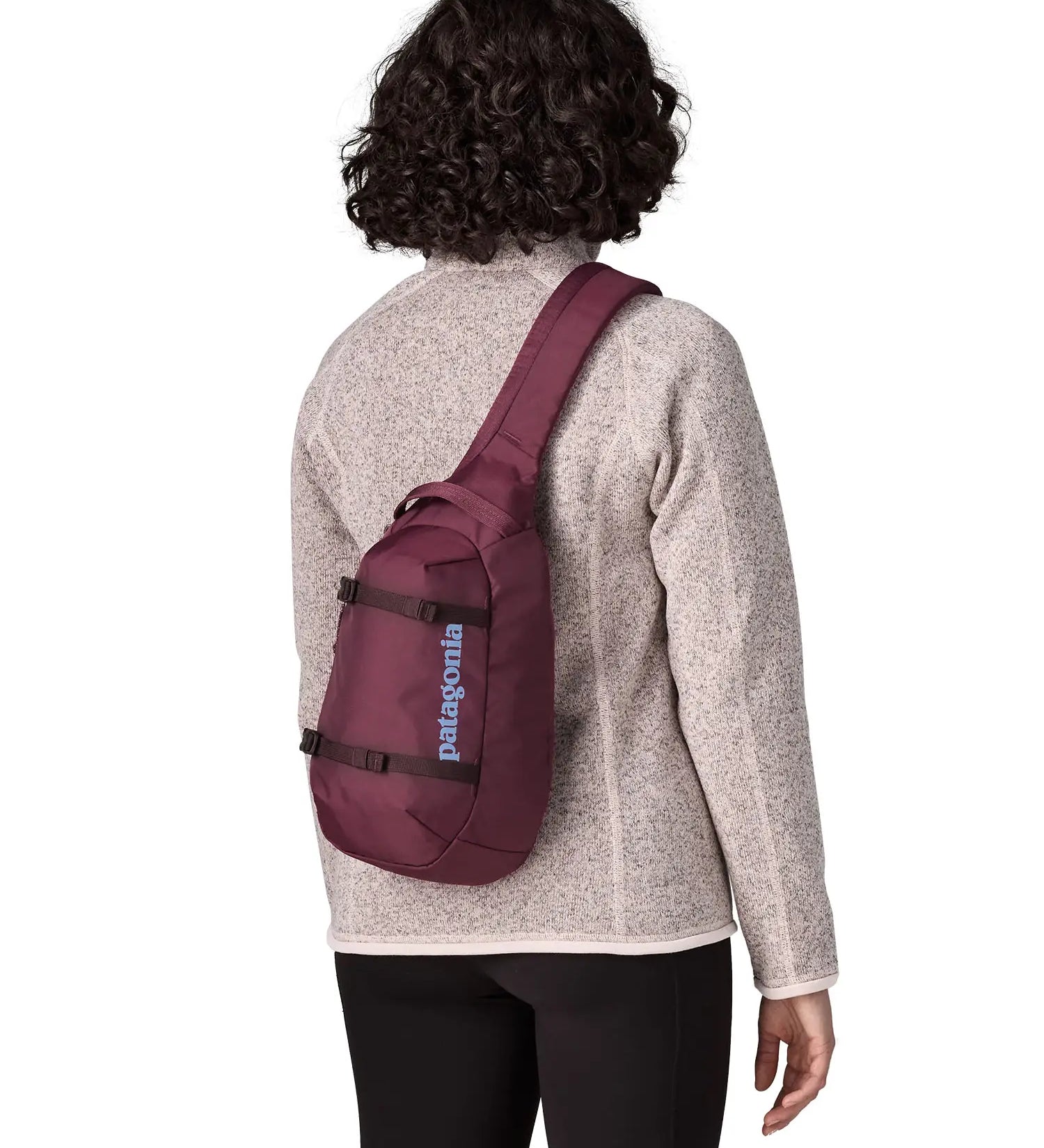 Person wearing a Patagonia atom sling 8L bag in berry fig on their back.