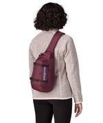 Person wearing a Patagonia atom sling 8L bag in berry fig on their back.
