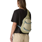 Back of woman wearing the Patagonia atom cross body 8L sling bag in pale green over the shoulder