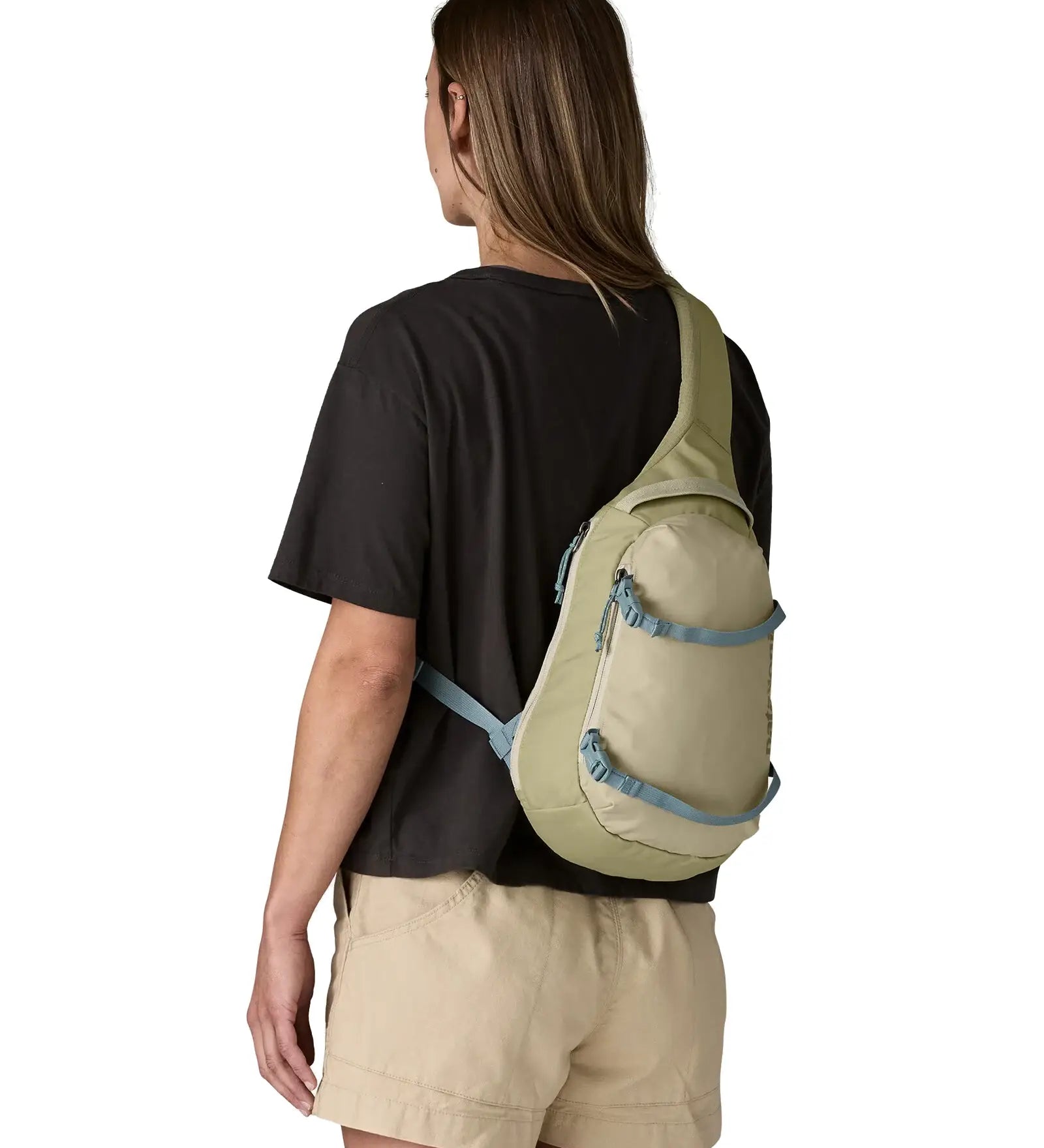 Back of woman wearing the Patagonia atom cross body 8L sling bag in pale green over the shoulder
