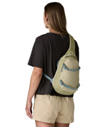 Back of woman wearing the Patagonia atom cross body 8L sling bag in pale green over the shoulder