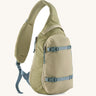 Patagonia atom cross body 8L sling bag in weathered stone with grey gear straps and buckles.