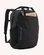 Patagonia atom 20 litre black tote bag backpack shown with stationery in the front pocket.