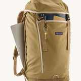 Patagonia lid fieldsmith lid backpack in classic tan with the side zip open for storing a laptop a clip for keys and a handy front compartments for maps and small notepads.
