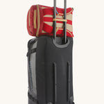 Patagonia Recycled Black Hole Backpack 25L in Touring Red hooked over the handle of a luggage roller case on a cream background 