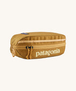 Patagonia cube Travel Bag 3L in a beeswax tan colour on a cream background.