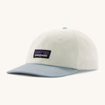 Patagonia trad cap in birch white and light blue on a cream background.