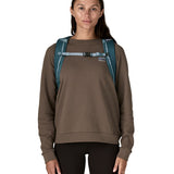 Front view of a woman wearing the Patagonia Black Hole Backpack 25L in Tidal Teal, to showcase the chest straps that keep the rucksack secure on adventures. 