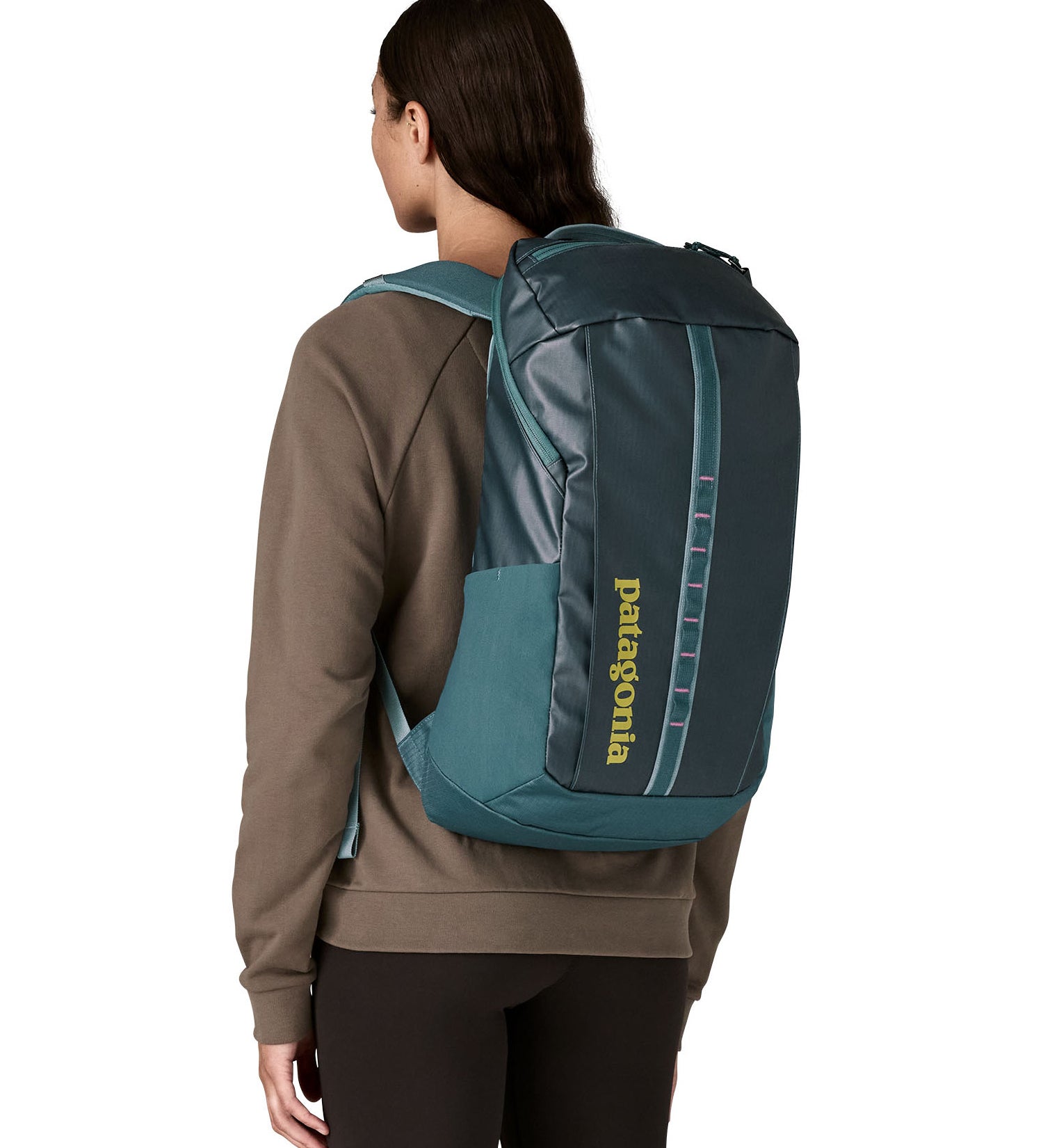 A woman wearing the Patagonia Black Hole Backpack 25L on her back, in a Tidal Teal blue colour palette. 