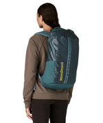 A woman wearing the Patagonia Black Hole Backpack 25L on her back, in a Tidal Teal blue colour palette. 