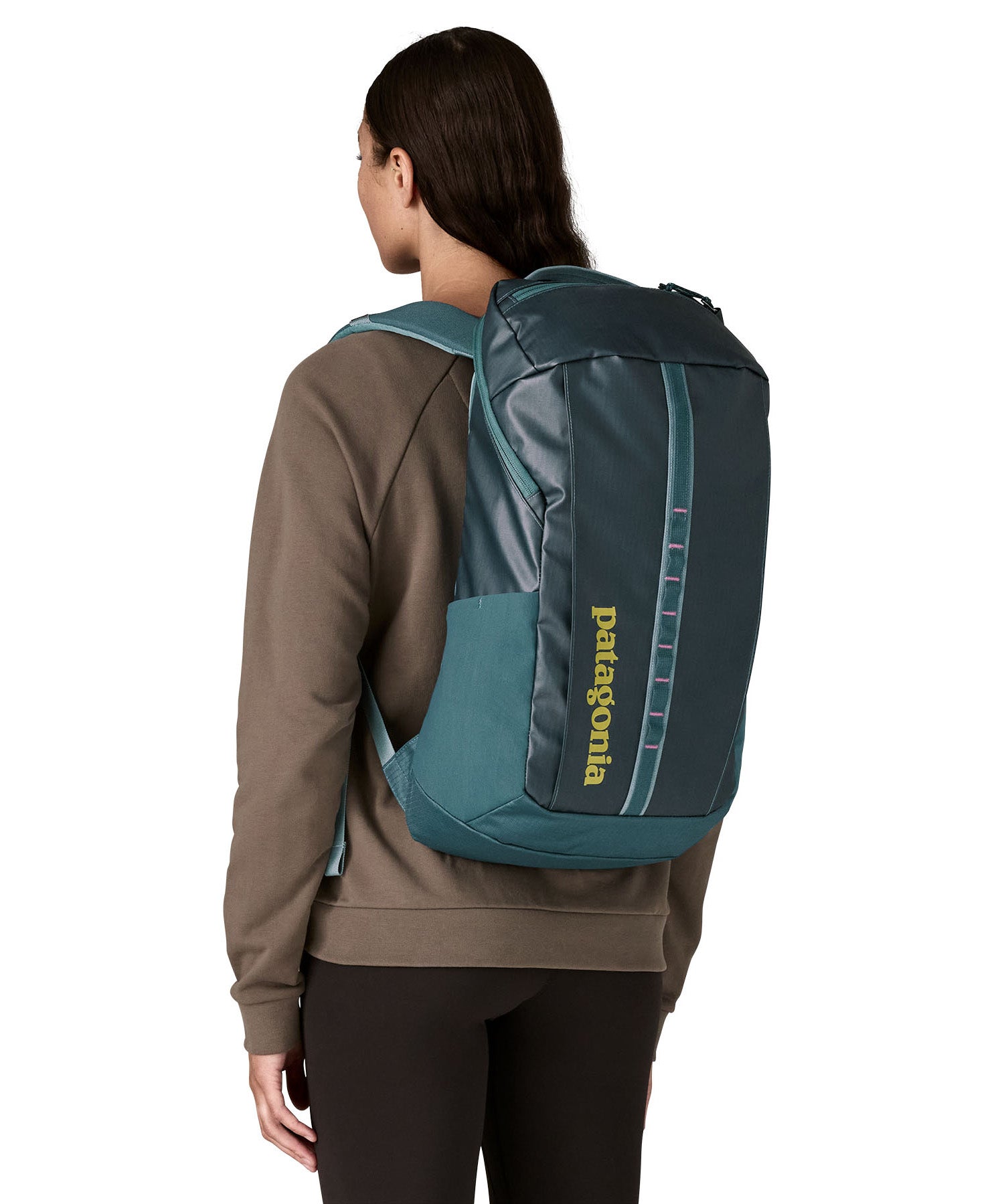 A woman wearing the Patagonia Black Hole Backpack 25L on her back, in a Tidal Teal blue colour palette. 