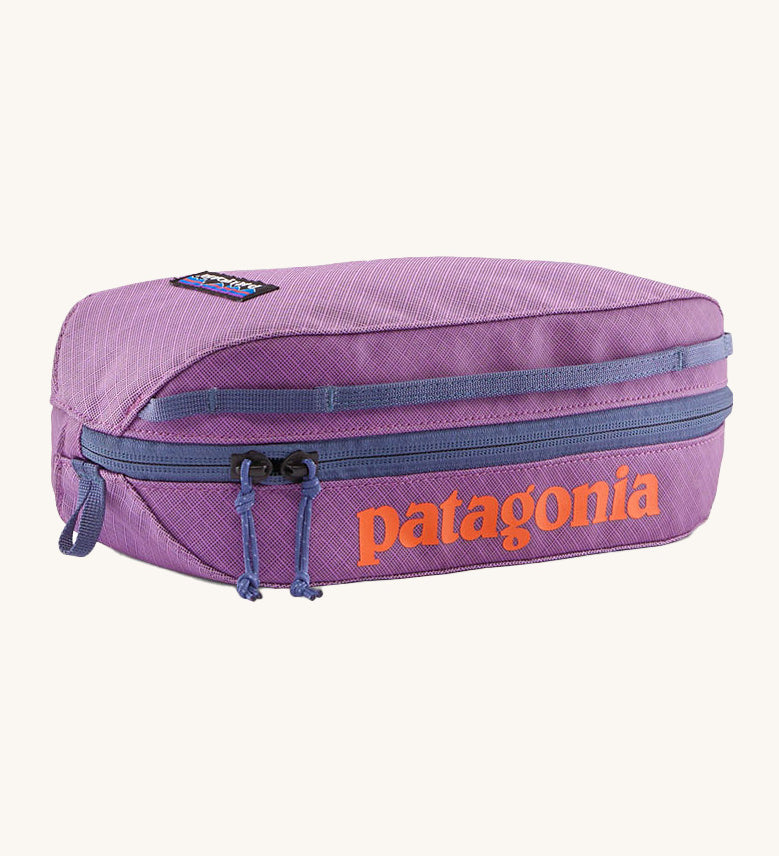 Patagonia 3L black hole cube bag in brisk purple. A 100% recycled bag in vibrant purple with a navy zip detail. Features a bran patch on side and  brand name print  in orange on the top side