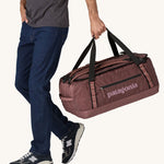A person holding a 55L Patagonia Black Hole Duffel bag.