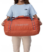A person holding a 55L Patagonia Black Hole Duffel bag.