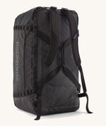 A back view of the large 100 litre capacity Patagonia Black Hole Duffel Luggage Bag, in monochrome all black., showing the shoulder straps. 