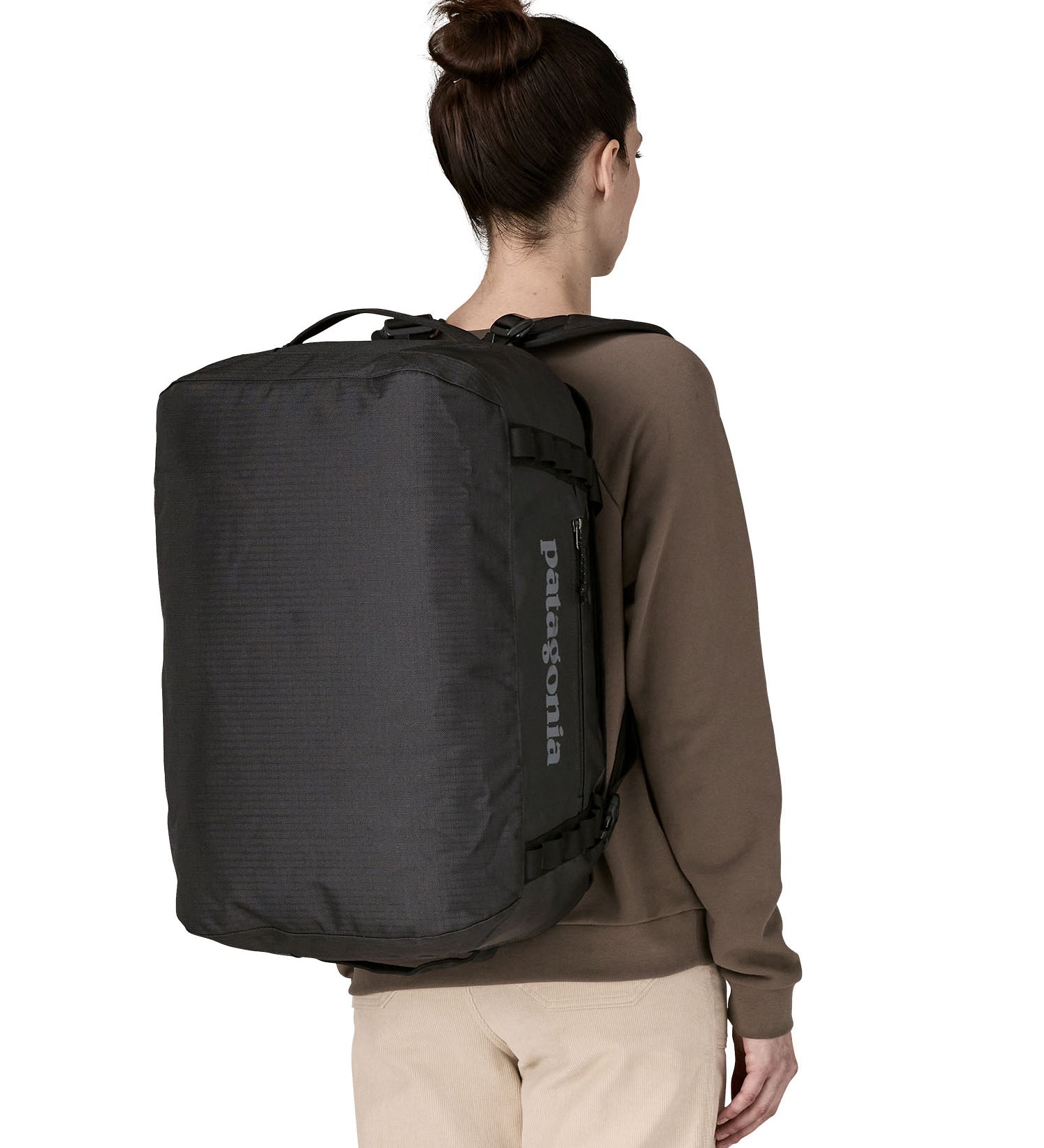 A woman wearing The Patagonia Black Hole 40 Litre Luggage Backpack in monochrome black on her back.