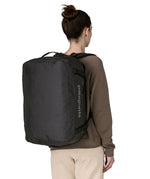 A woman wearing The Patagonia Black Hole 40 Litre Luggage Backpack in monochrome black on her back.