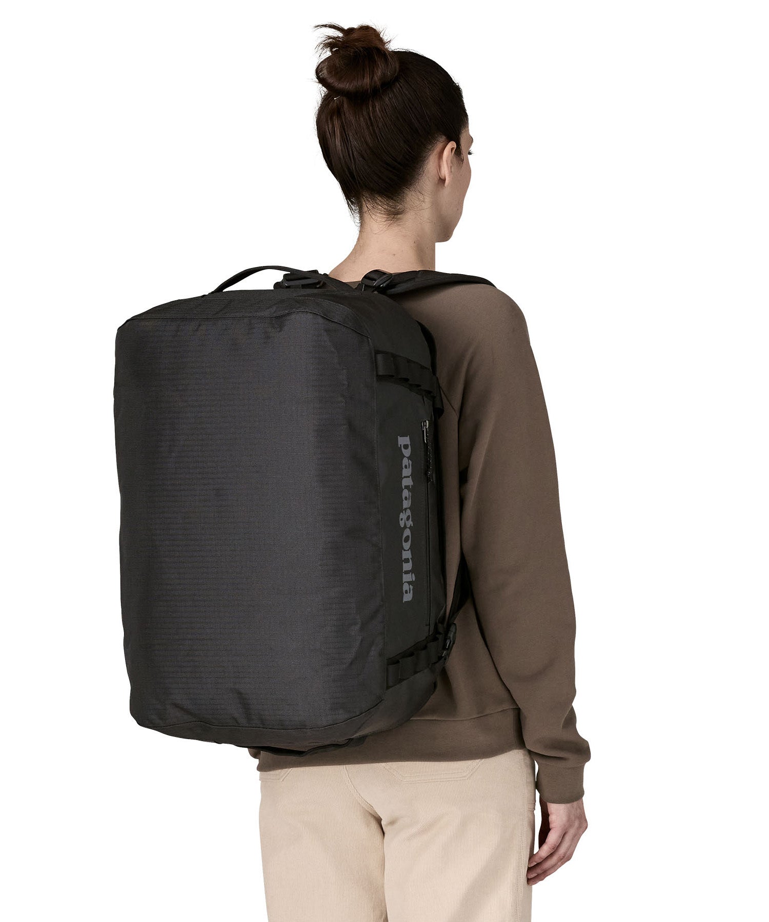 A woman wearing The Patagonia Black Hole 40 Litre Luggage Backpack in monochrome black on her back.