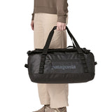 A person holding The Patagonia Black Hole 40 Litre Luggage Backpack in monochrome black.