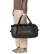 A person holding The Patagonia Black Hole 40 Litre Luggage Backpack in monochrome black.