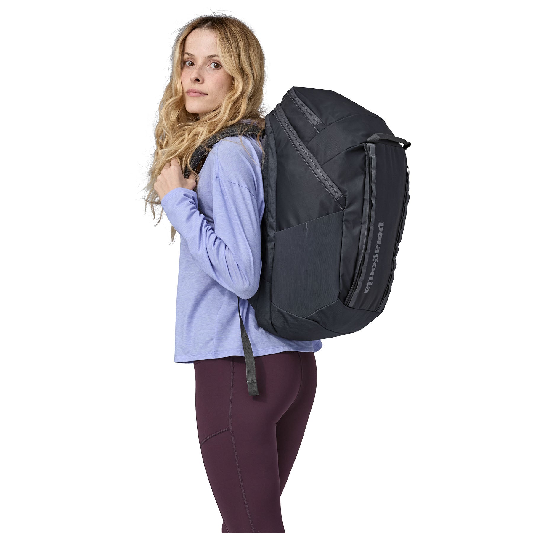 A side view of a woman wearing The Patagonia Black Hole Pack 32 litre capacity backpack in smolder slate-blue