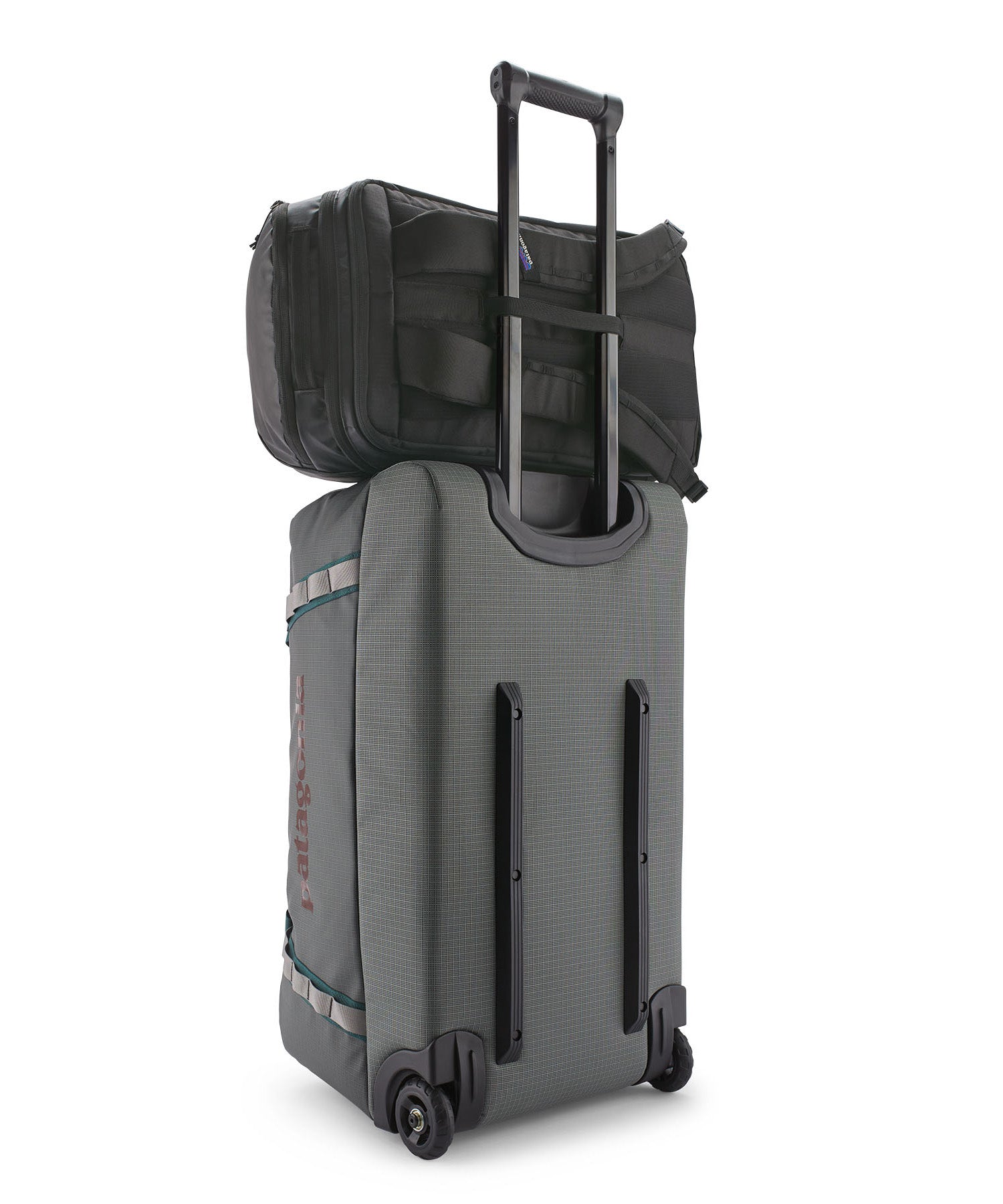 Patagonia Black Hole Pack 32L black attached securely to rolling luggage handle for easy travel.