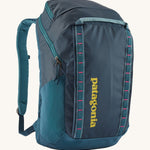 Patagonia 32L black hole backpack in a tidal teal colour on a cream background.