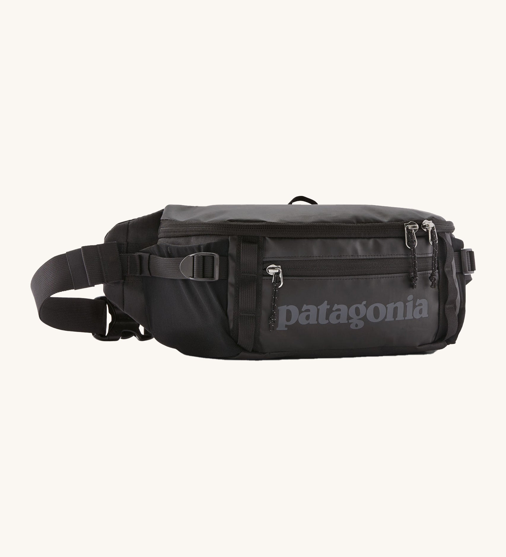 Patagonia black hole waist 5L pack in black on black. A 100% recycled nylon pack in black with black detail. Features 2 compartments with mesh side pockets and a buckle fastener 