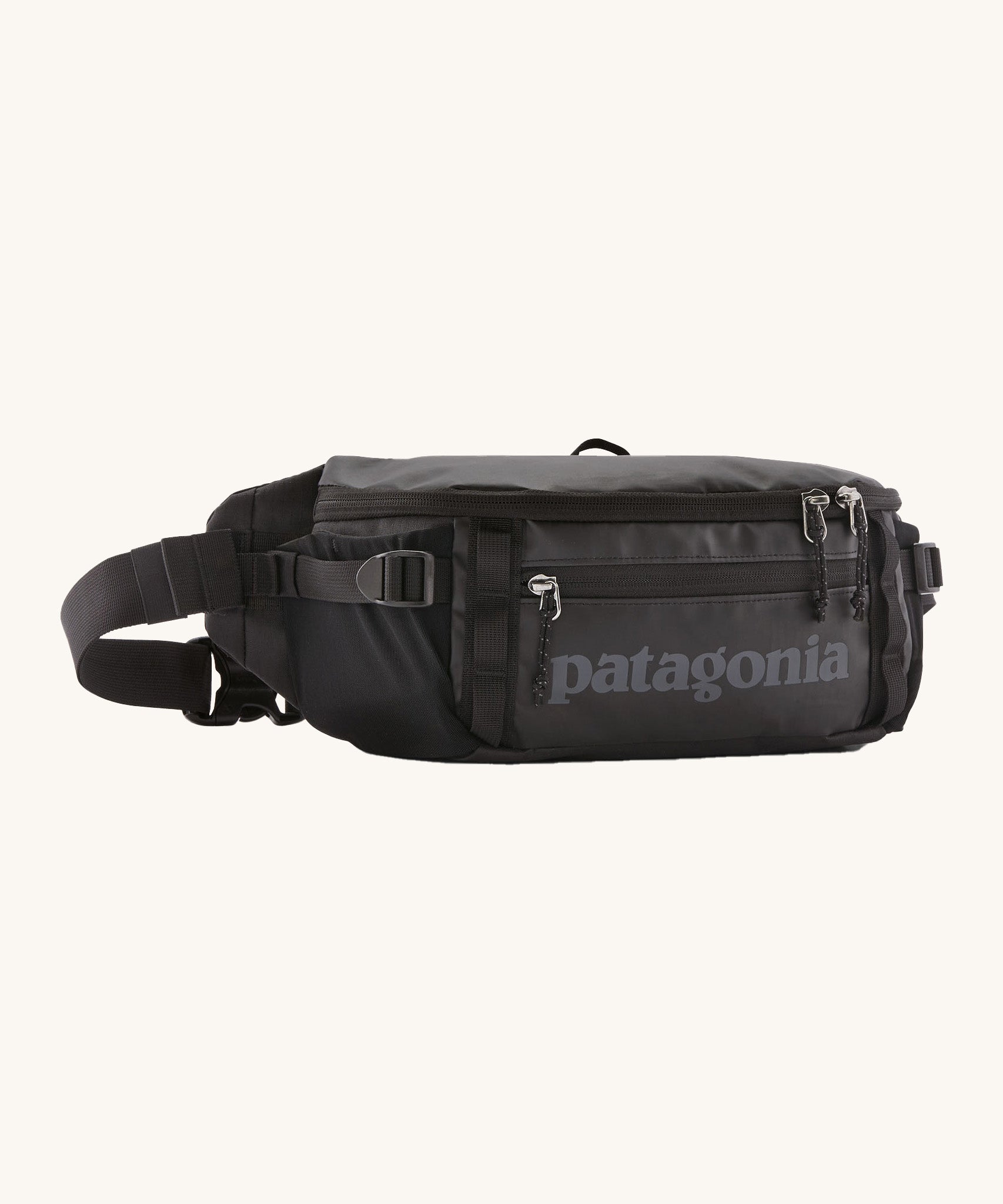 Patagonia black hole waist 5L pack in black on black. A 100% recycled nylon pack in black with black detail. Features 2 compartments with mesh side pockets and a buckle fastener 