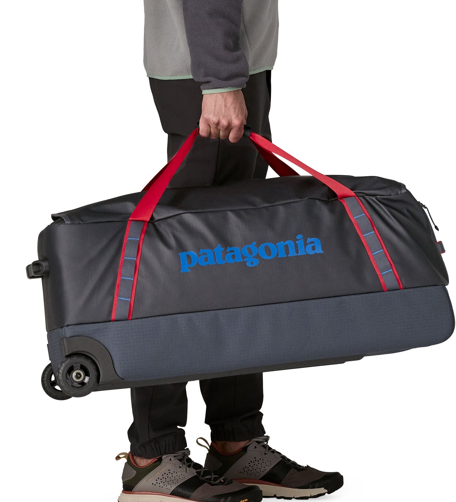 Patagonia black hole wheeled large capacity 100L duffel bag in black with red strap carry handles and blue logo on front.