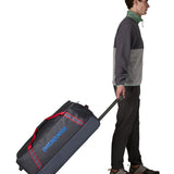 Person pulling along a Patagonia black hole wheeled large capacity 100L duffel bag in black by the retractable handle.
