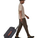 Patagonia 40L black hole wheeled duffel bag being pulled by an adult
