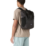 Patagonia Terravia tote bag in black worn by a adult on the back showing the carrying handle details and side pockets for holding bottles