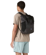 Patagonia Terravia tote bag in black worn by a adult on the back showing the carrying handle details and side pockets for holding bottles