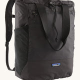 Patagonia Terravia tote bag in black showing the front zip and strap details with the brand log on the bottom panel. Features shoulder straps for easy carrying.