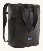 Patagonia Terravia tote bag in black showing the front zip and strap details with the brand log on the bottom panel. Features shoulder straps for easy carrying.