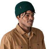 A man wearing the Patagonia adult brodeo beanie hat on cascade green. A soft knit style beanie with turn up brim and logo patch on the side available at Babipur.